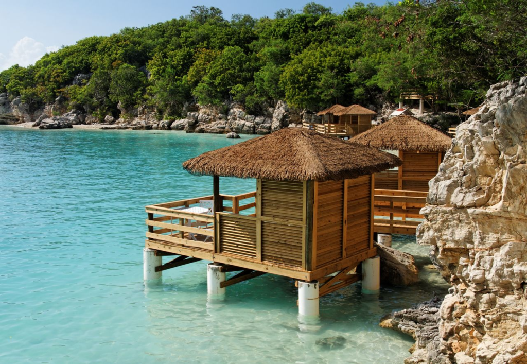 Scenic view of thatched huts on stilts over turquoise waters along the Haitian coast.
